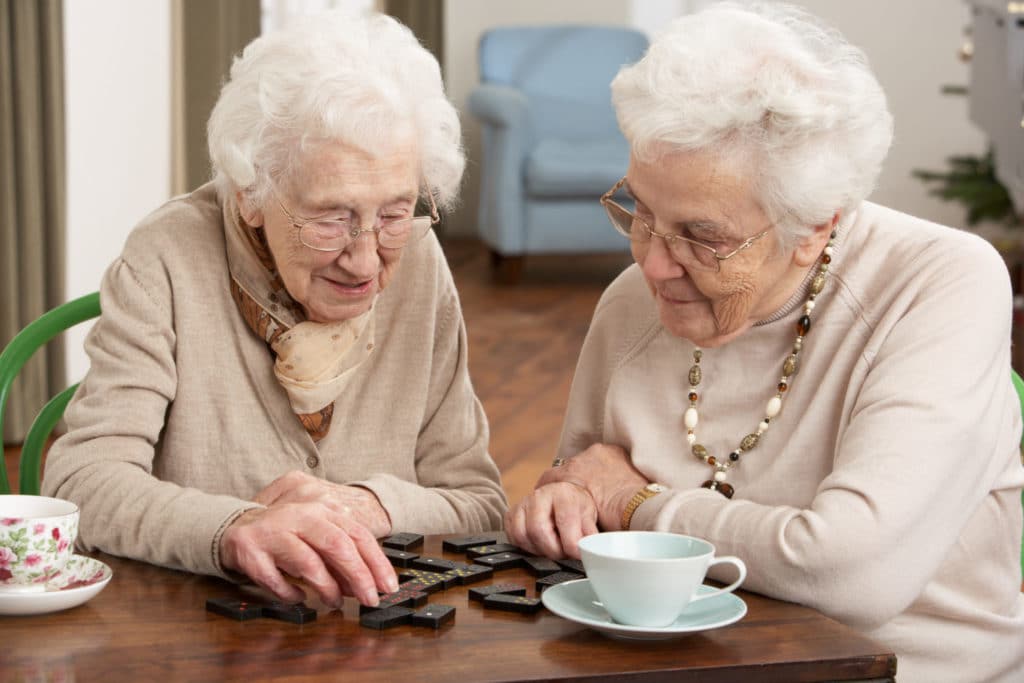 Two Senior Women Playing Dominoes At Day Care Center